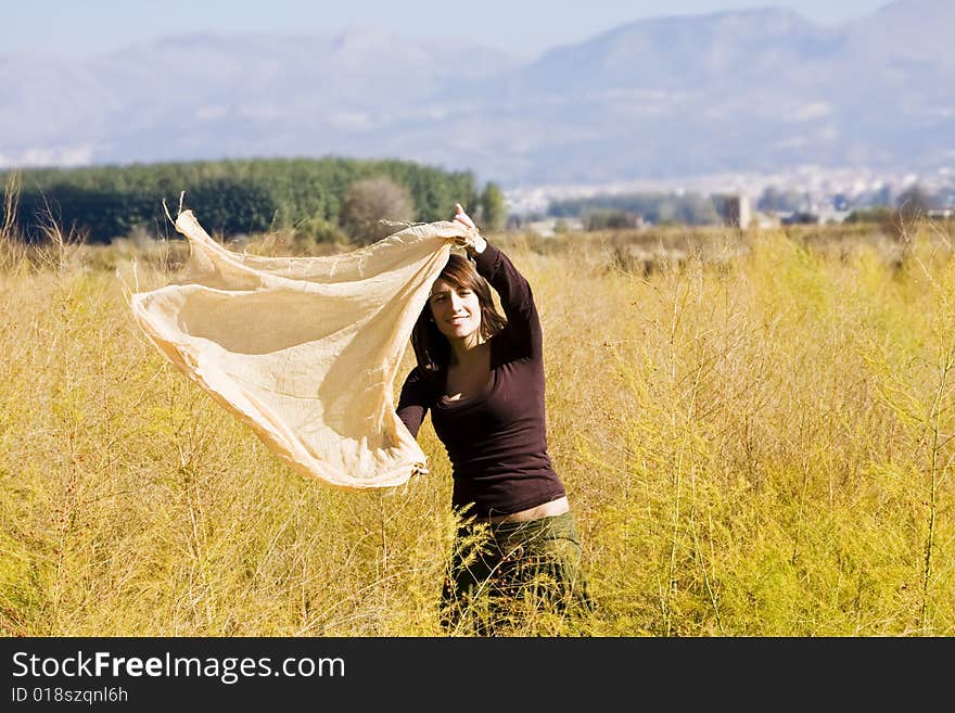 Young woman dancing with scarf in a field. Young woman dancing with scarf in a field.