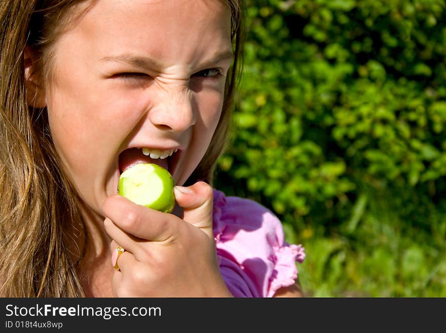 Little girl biting green apple. Little girl biting green apple