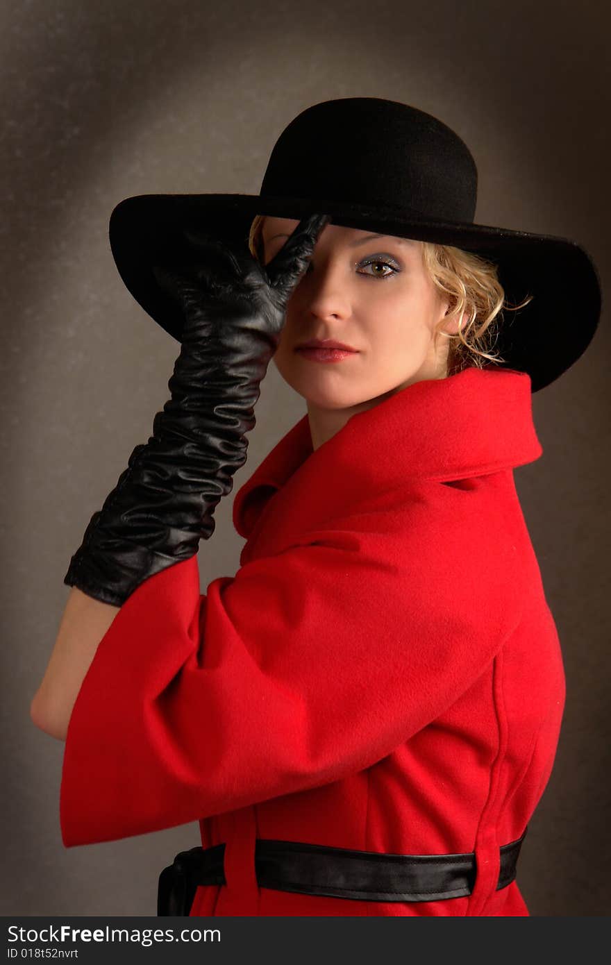 Young woman looking in front of her with interest raising brim of her hat with finger. Young woman looking in front of her with interest raising brim of her hat with finger