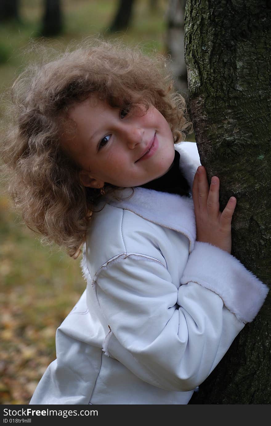 Little girl in a park next to a birch