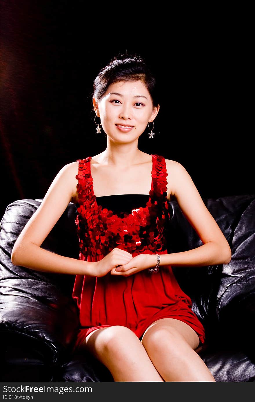 Asian female model in red skirt sitting on sofa. Asian female model in red skirt sitting on sofa