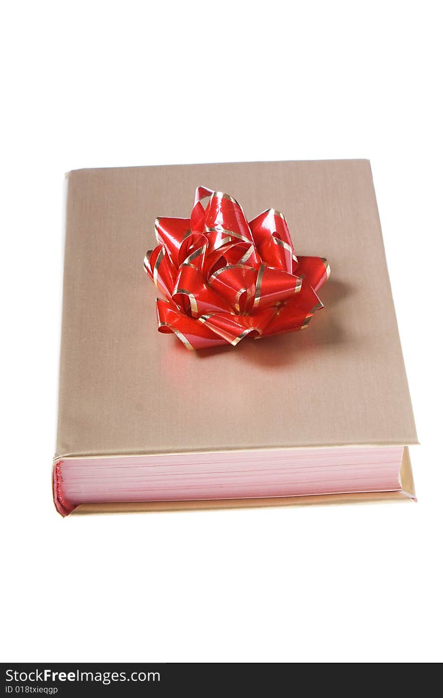 Book wrapped golden paper with red and yellow bow on top. Book wrapped golden paper with red and yellow bow on top