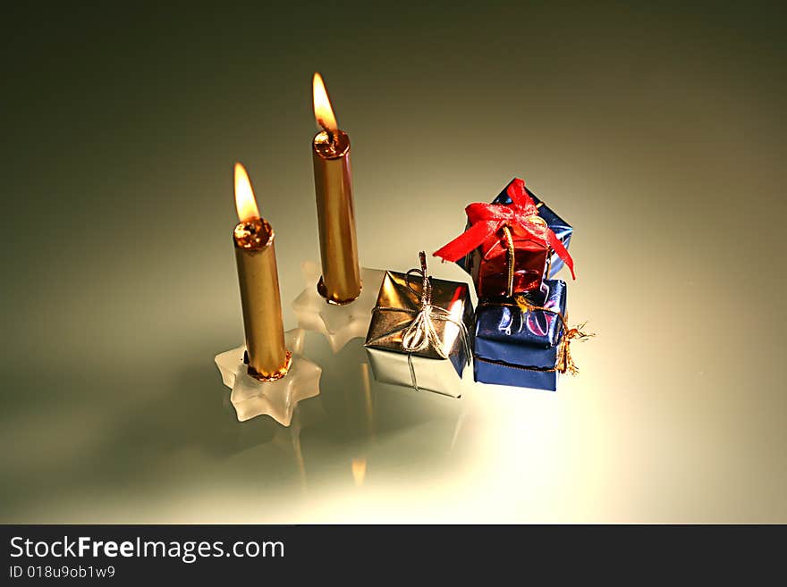 Chritmas candles and gifts and reflection in glass table with warm light