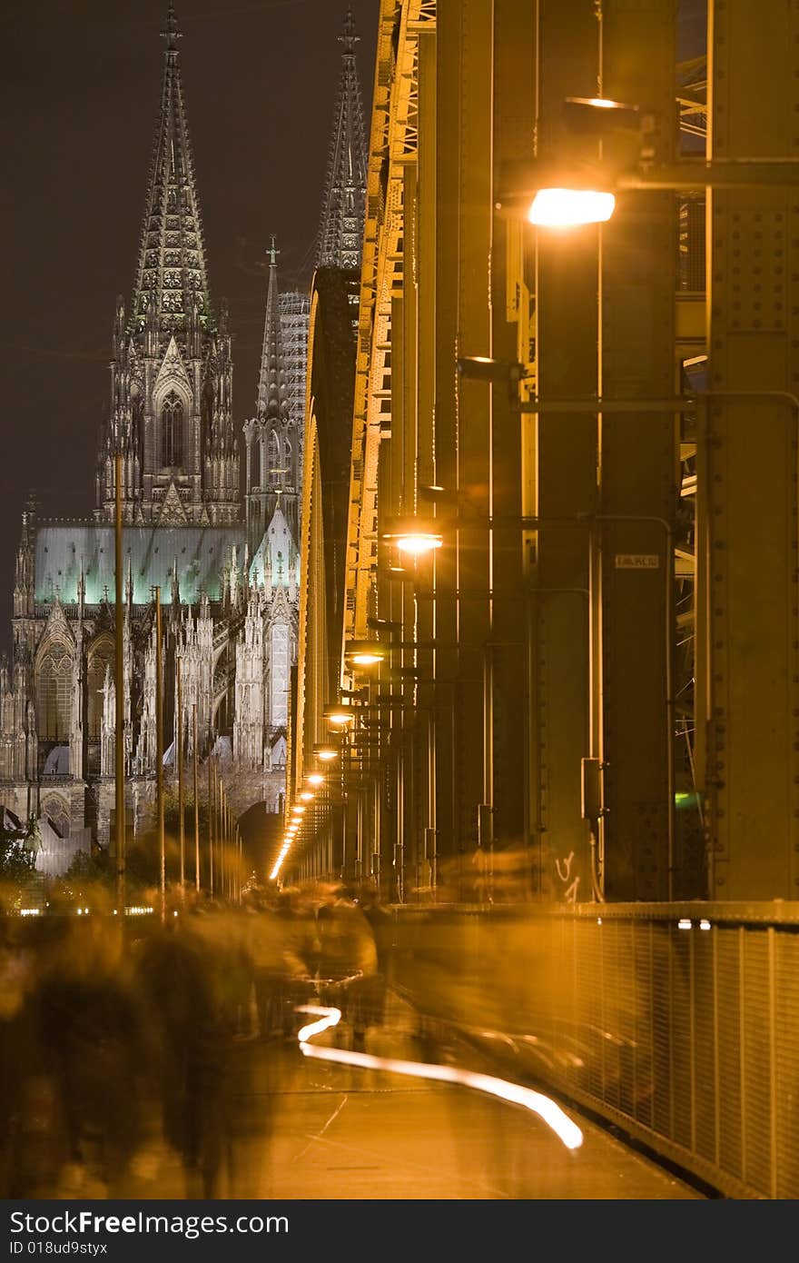 Dom in Cologne with arcs of Hohenzollern bridge, shadows of people walking on the bridge and bycycle light track. Dom in Cologne with arcs of Hohenzollern bridge, shadows of people walking on the bridge and bycycle light track.