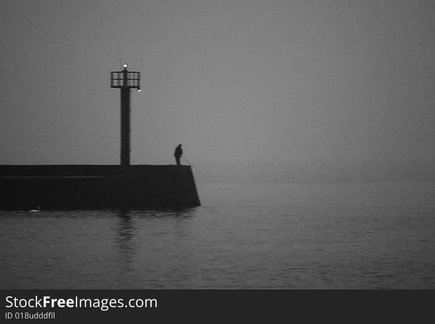 A fisherman on the pier. Noise imitate the film and film are intentional.