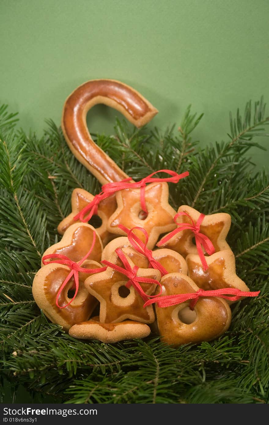 A pile of gingerbread cookies nestled in nest of fir branches and isolated on green paper. A pile of gingerbread cookies nestled in nest of fir branches and isolated on green paper