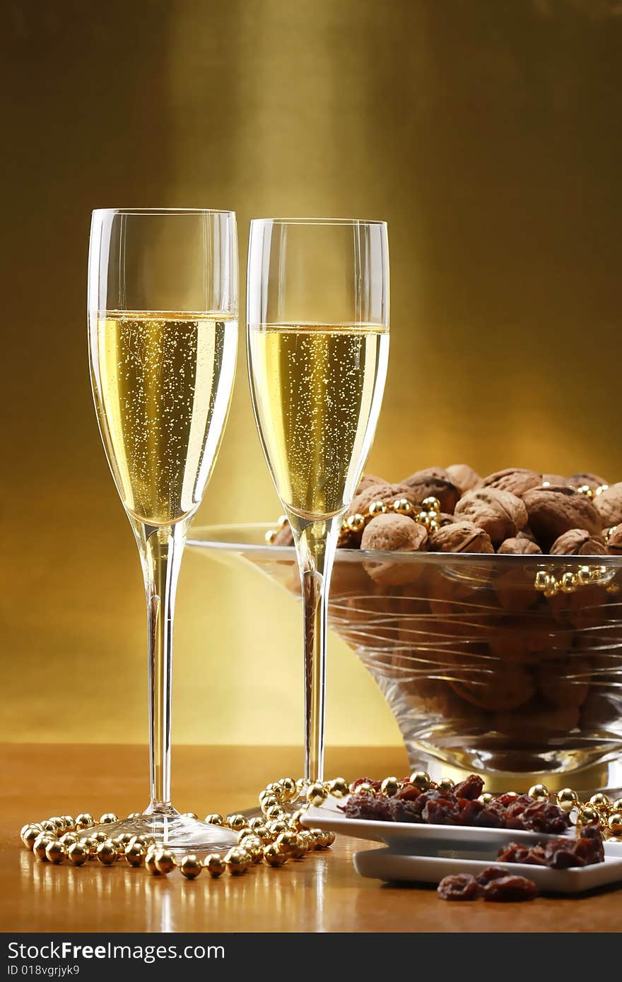 Glasses of champagne with gold background with walnuts, candels and dried raisins