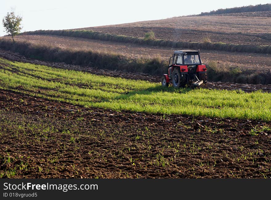 Red-black tractor working on a field