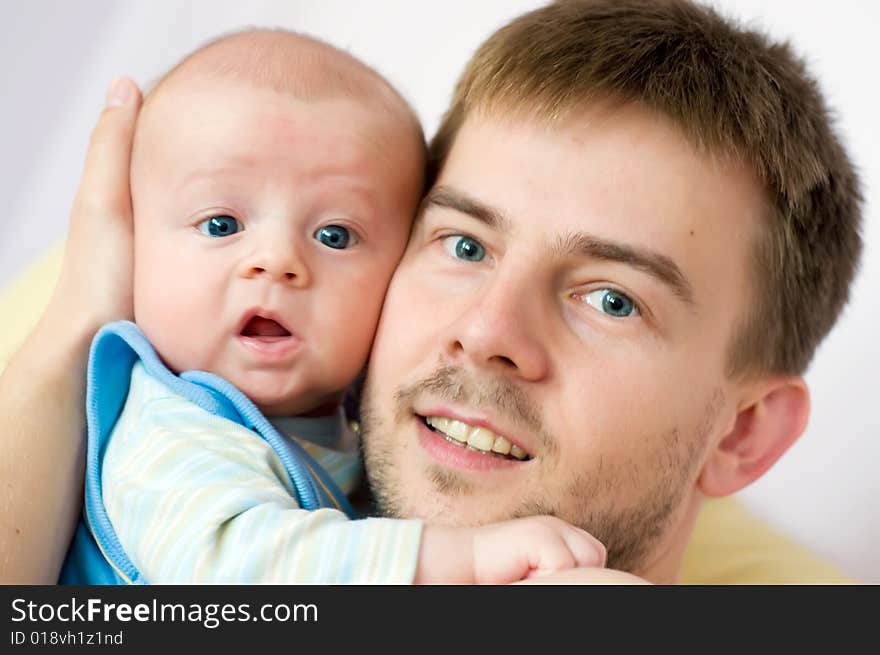 Baby embraced by its father. Both are lookling straight into camera. Baby embraced by its father. Both are lookling straight into camera.