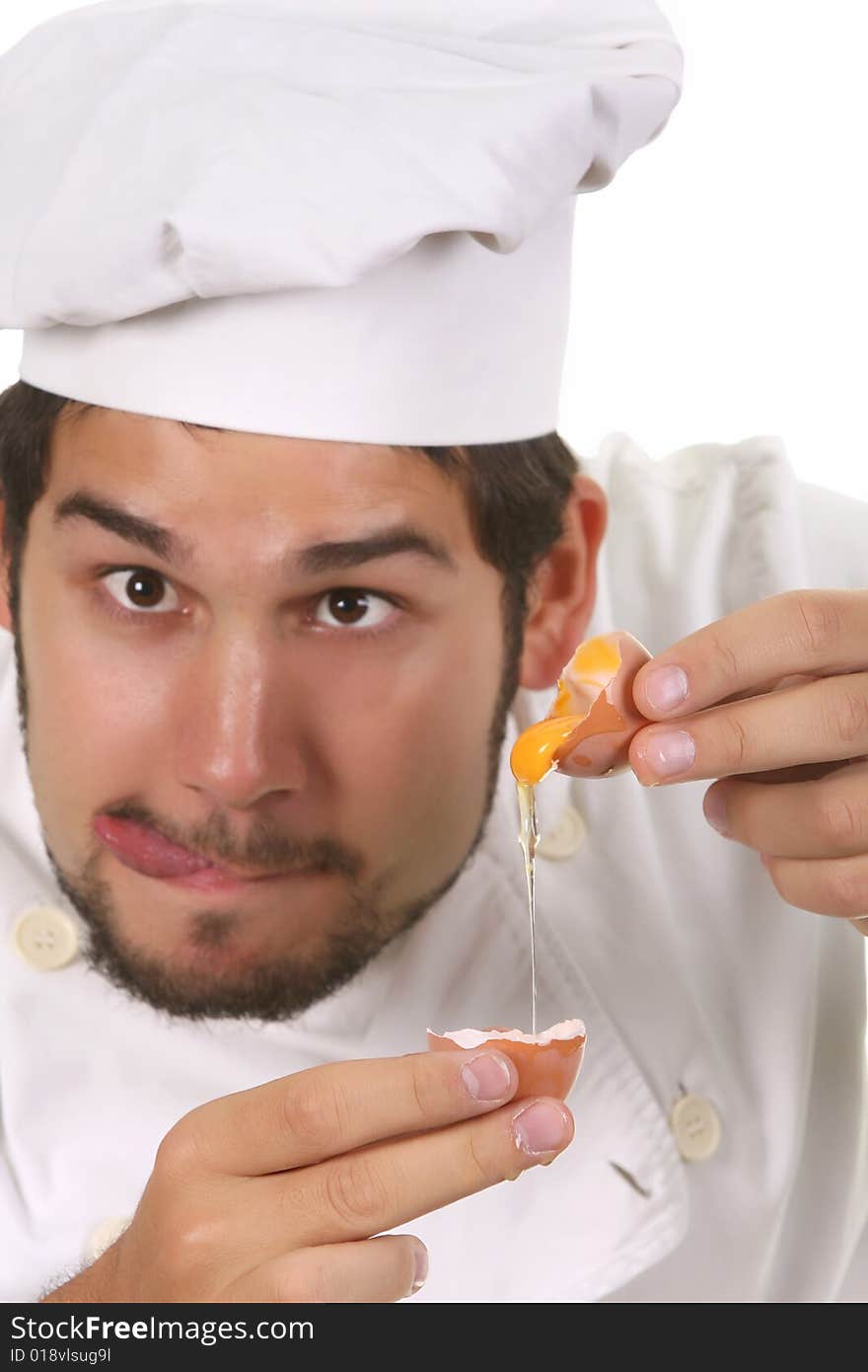 Young funny chef cracking an egg, focus on egg