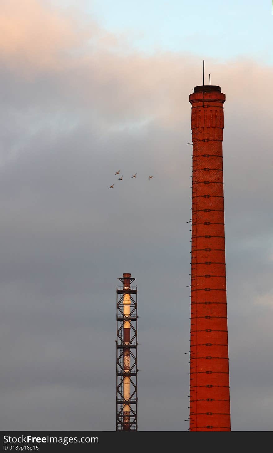 Two industrial stacks. The crowd of birds flying by. Two industrial stacks. The crowd of birds flying by.