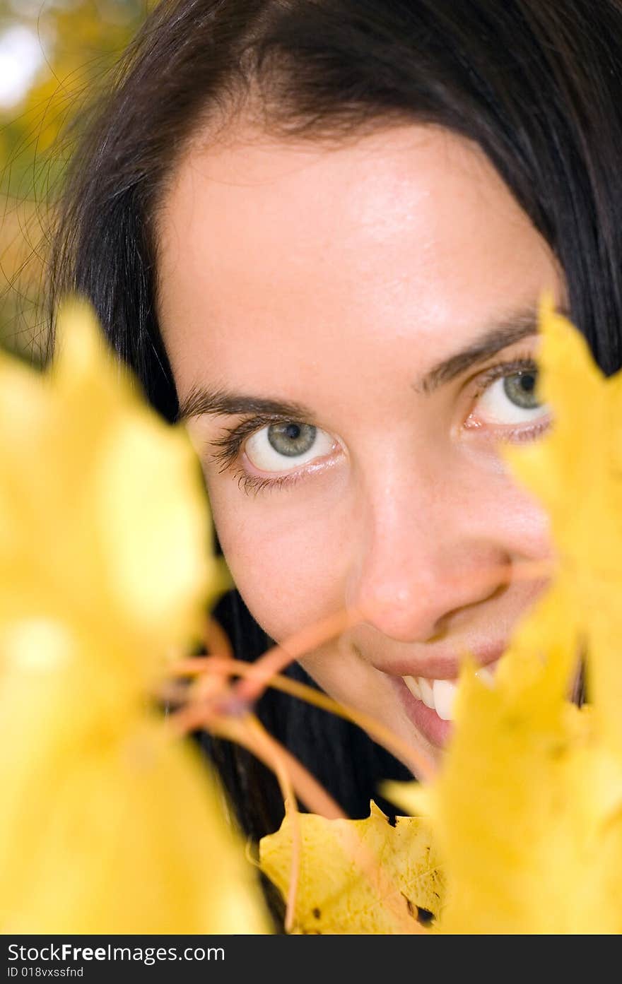 Beautiful young woman with golden leaves