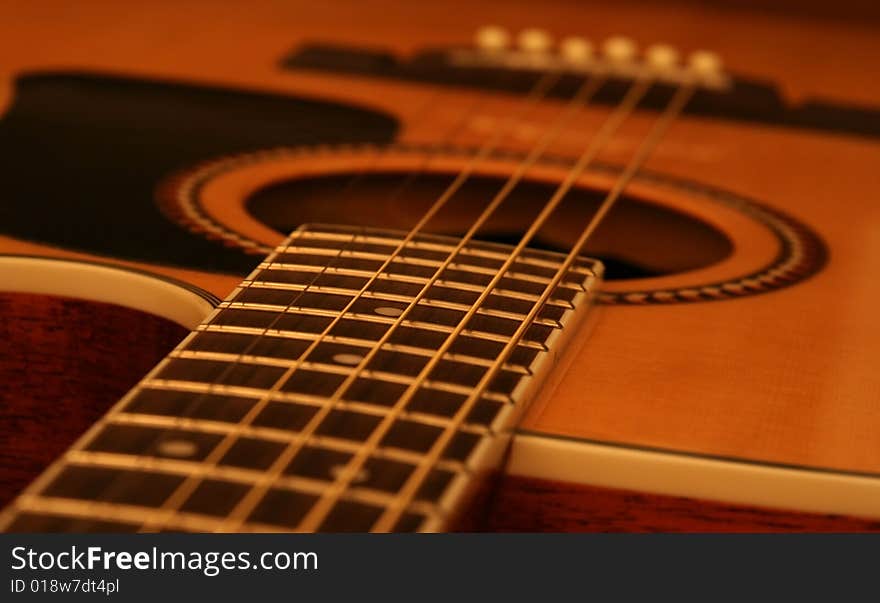 Steel and brass strings and guitar body close up under subdued lighting. Steel and brass strings and guitar body close up under subdued lighting.