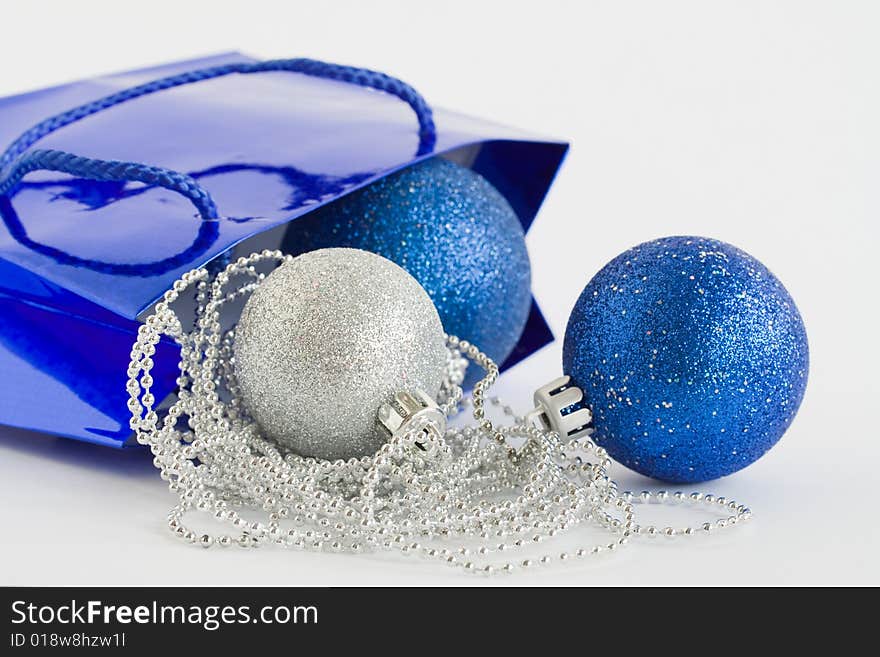 Blue bag, christmas balls and glass beads on white background