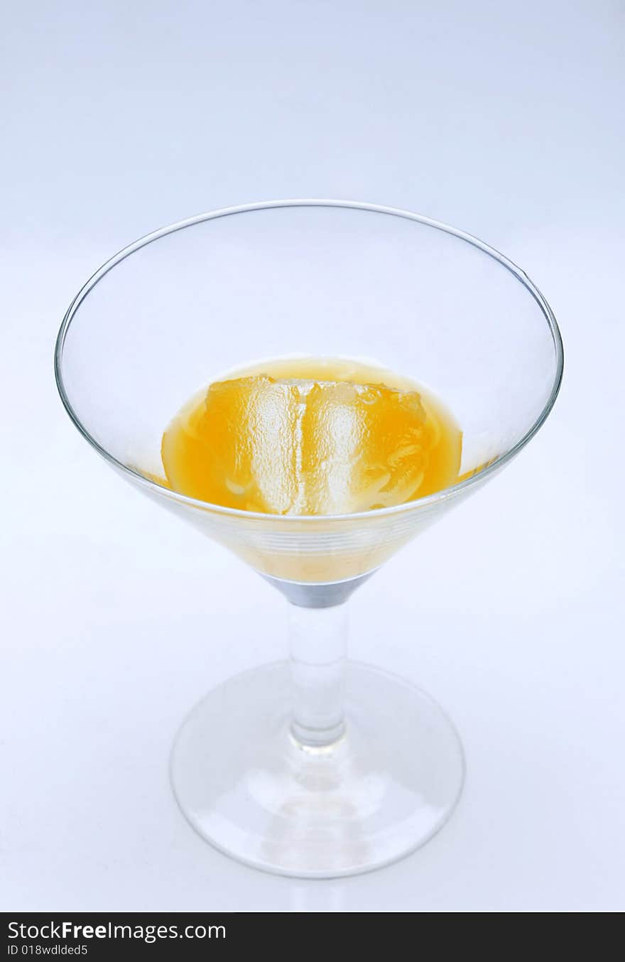 Cocktail glass with mango juice and ice standing on a light blue background. Cocktail glass with mango juice and ice standing on a light blue background