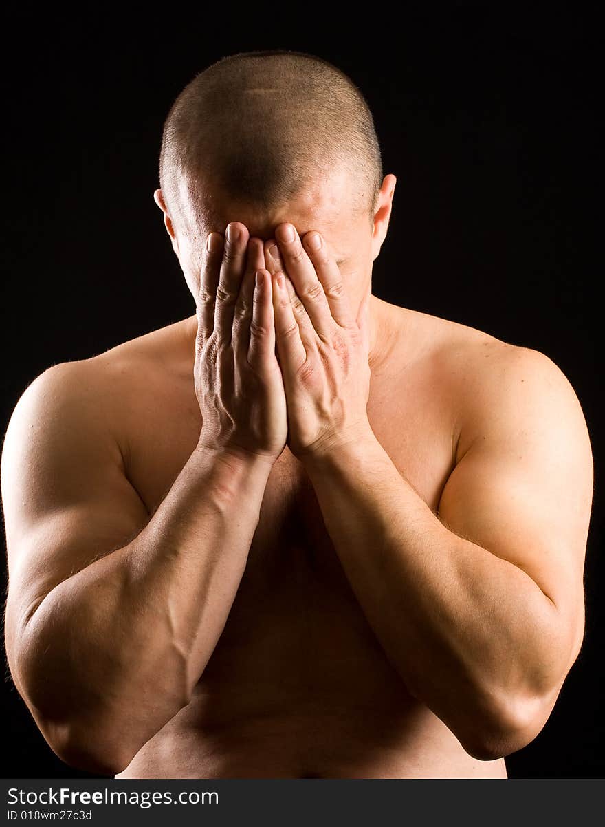 Muscular man covering his face with the hands