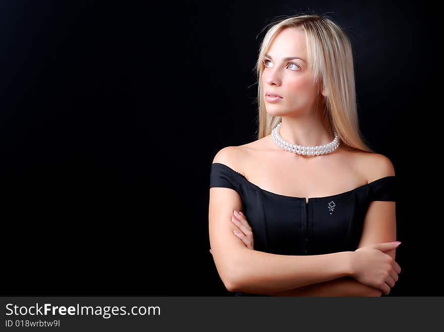 Beautiful young woman in black dress and pearl necklace