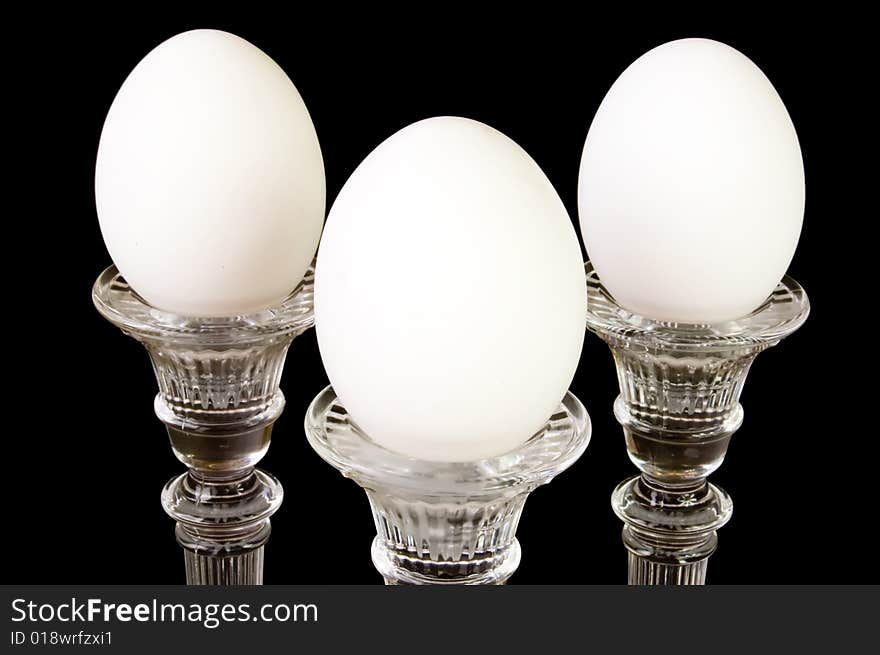 Three eggs on a pedestal, in a triangle formation, on a black background. Three eggs on a pedestal, in a triangle formation, on a black background