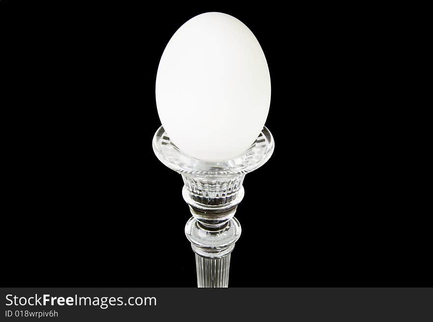 A single egg on a pedestal, on a black background