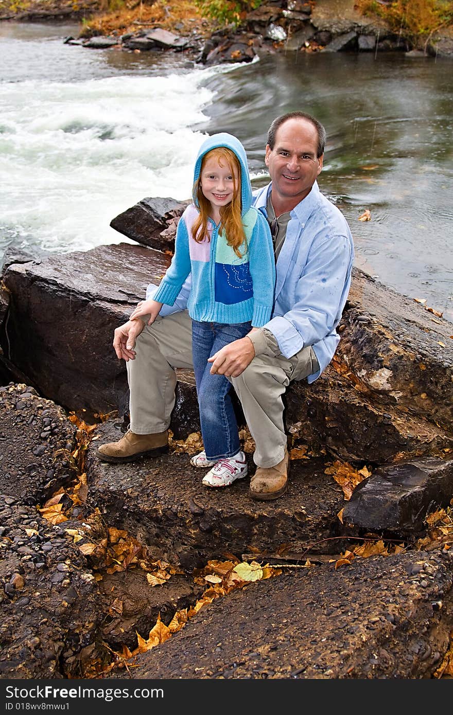 A small girl poses for a photograph after hiking down to the river on a fall day. A small girl poses for a photograph after hiking down to the river on a fall day.