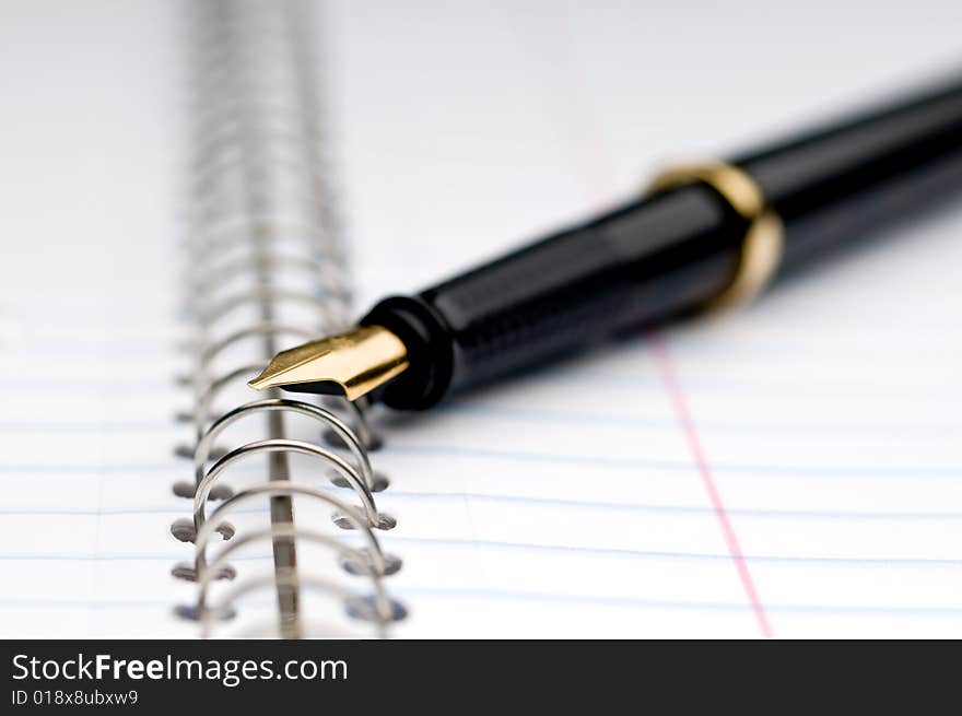 Shallow focus macro of a fountain pen on a spiral bound notebook