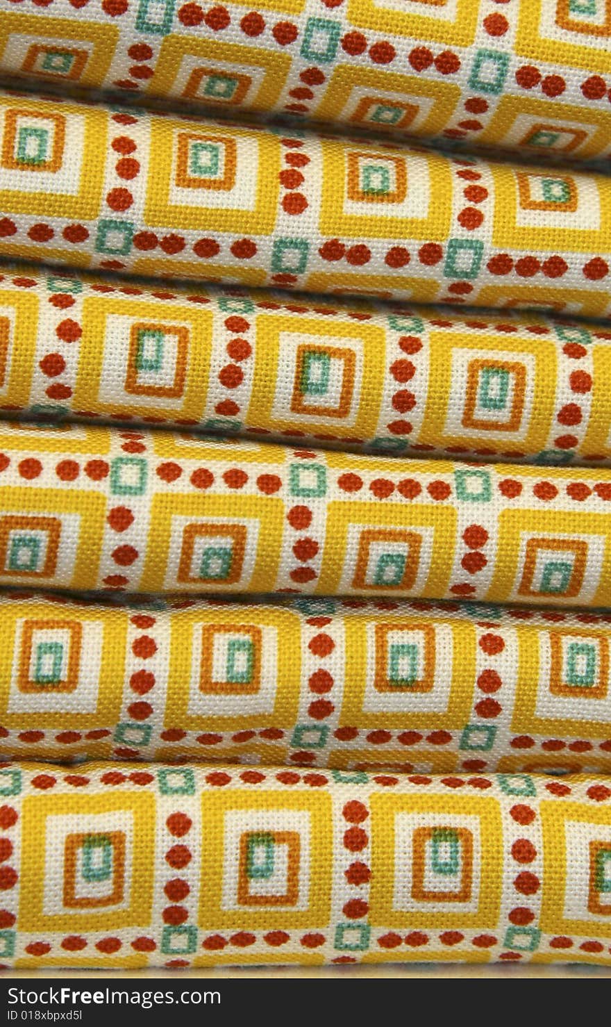 Stacks of yellow quilt fabric with bold yellow, red, orange and blue design