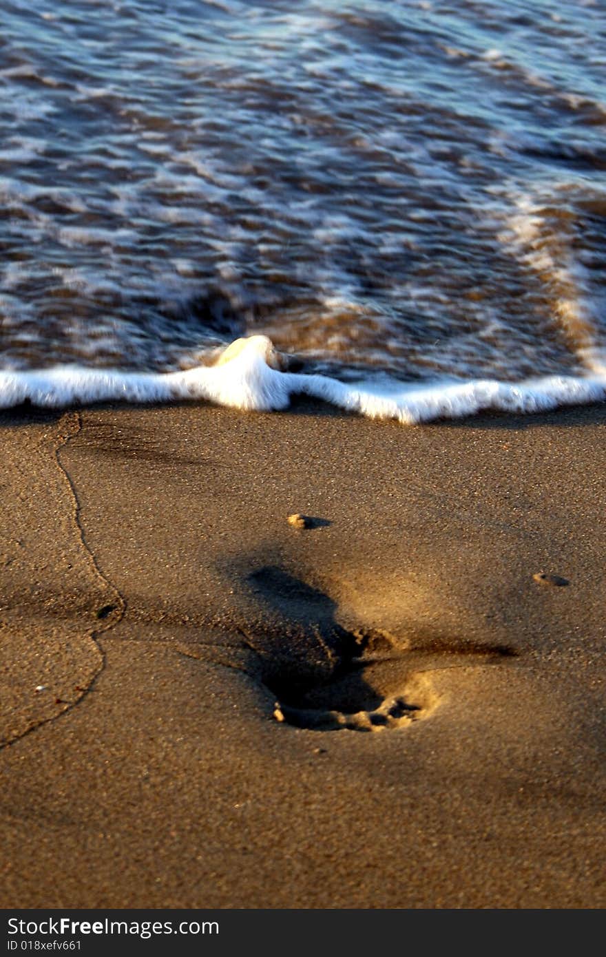 Waves washing away footprints on the beach. Waves washing away footprints on the beach