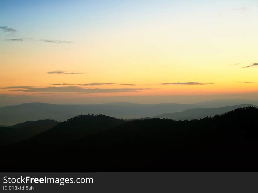 Silhouettes of mountains on background of sunrise