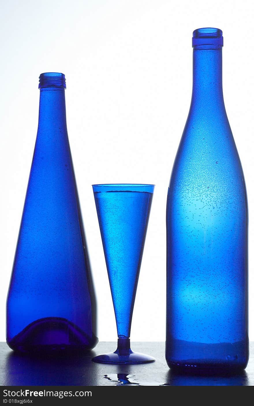 Two dark blue bottles and glass with water