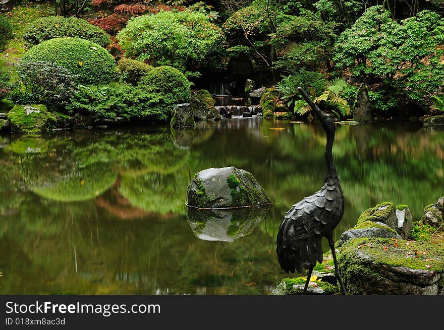 Stone bird statue with reflection of trees and distant fountain. Stone bird statue with reflection of trees and distant fountain