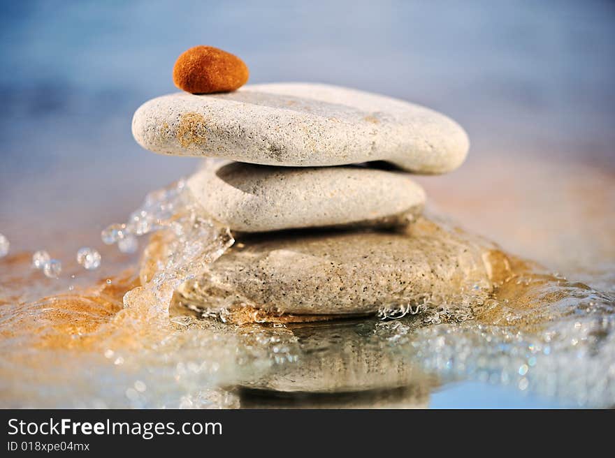 The pile of stones is reflected in a sea wave in the summer. The pile of stones is reflected in a sea wave in the summer