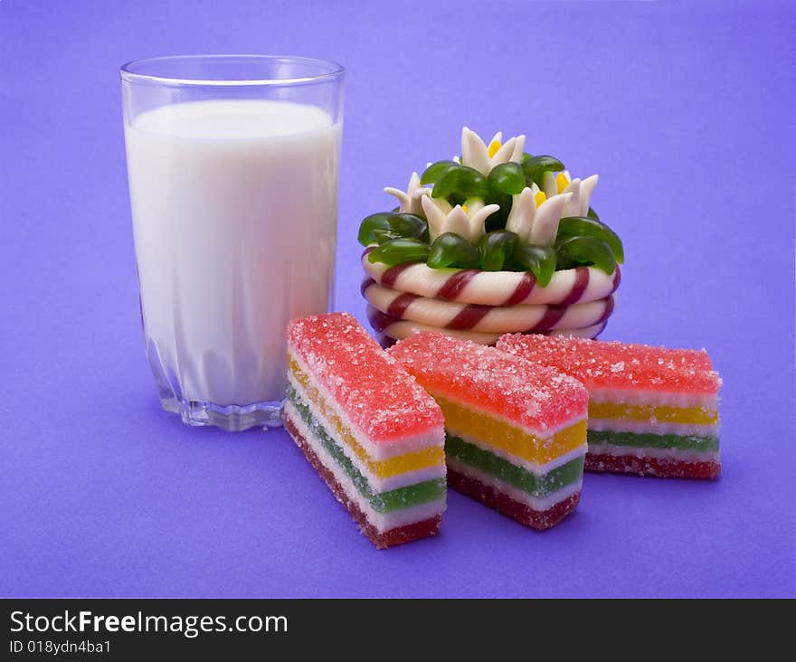 Fruit jellies and milk glass close-up isolated on violet background