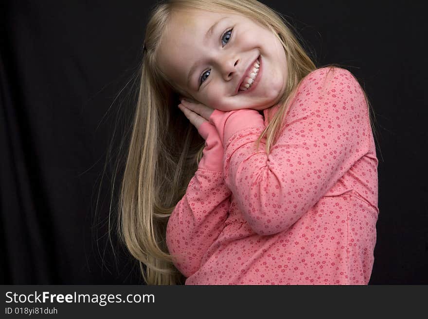 A very happy young girl with her head leaning on her hands. Isolated on black background. A very happy young girl with her head leaning on her hands. Isolated on black background.