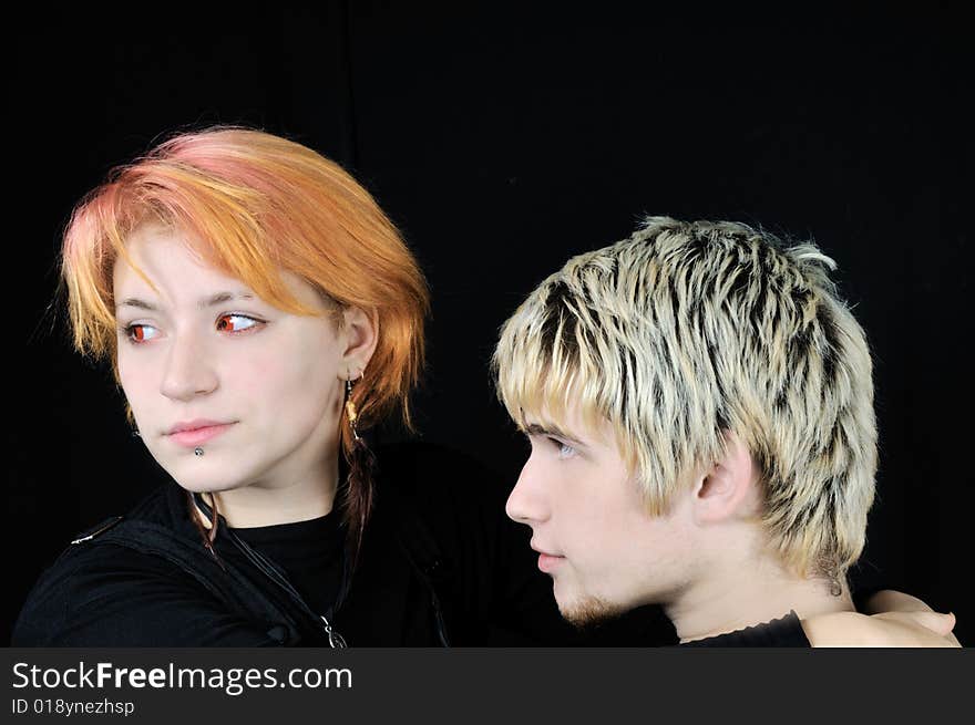 Pretty red-eyed vampire girl and a young guy, on black background