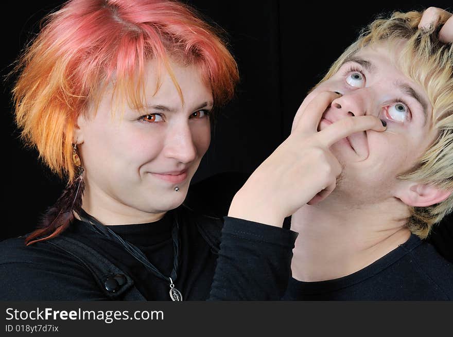 Red eyed young girl scratches out guy's eyes, on black background