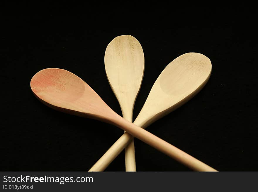 Three wooden spoons crossed on a black background. Three wooden spoons crossed on a black background