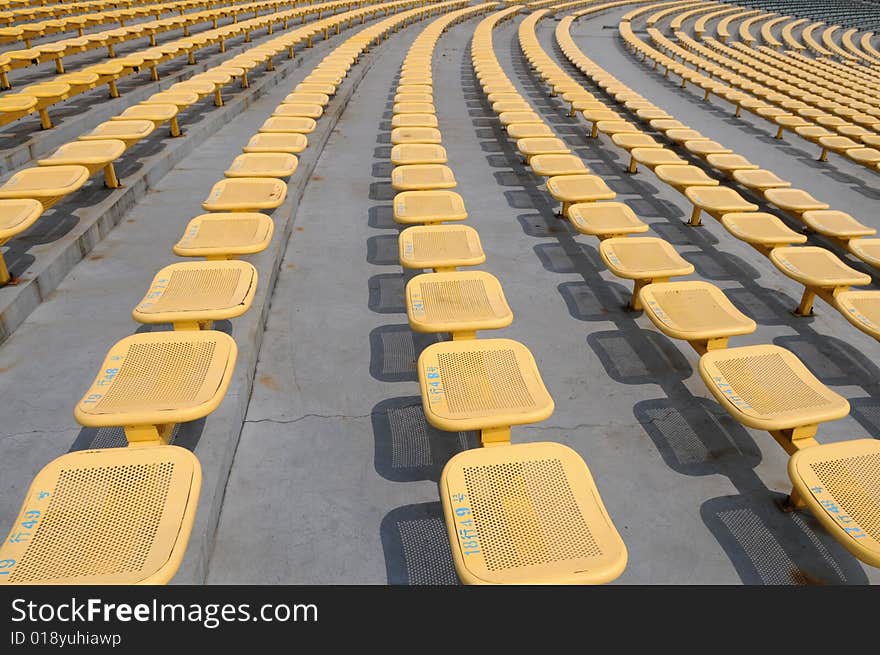 The parallel lines of yellow iron seats in an open stadium. The parallel lines of yellow iron seats in an open stadium.