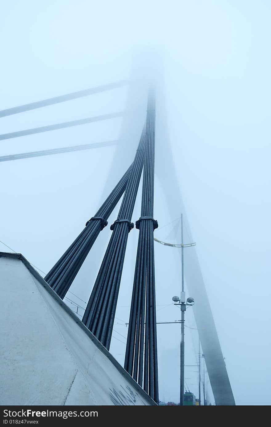 Industrial constructions are in fog, details of bridge are in a grey color