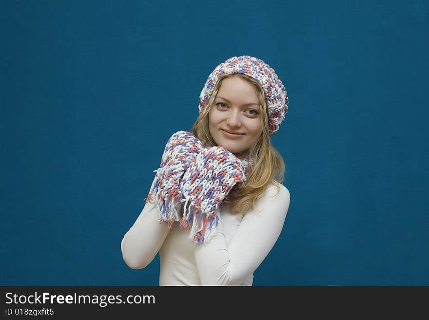 Portrait of a young girl in winter clothes on blue background