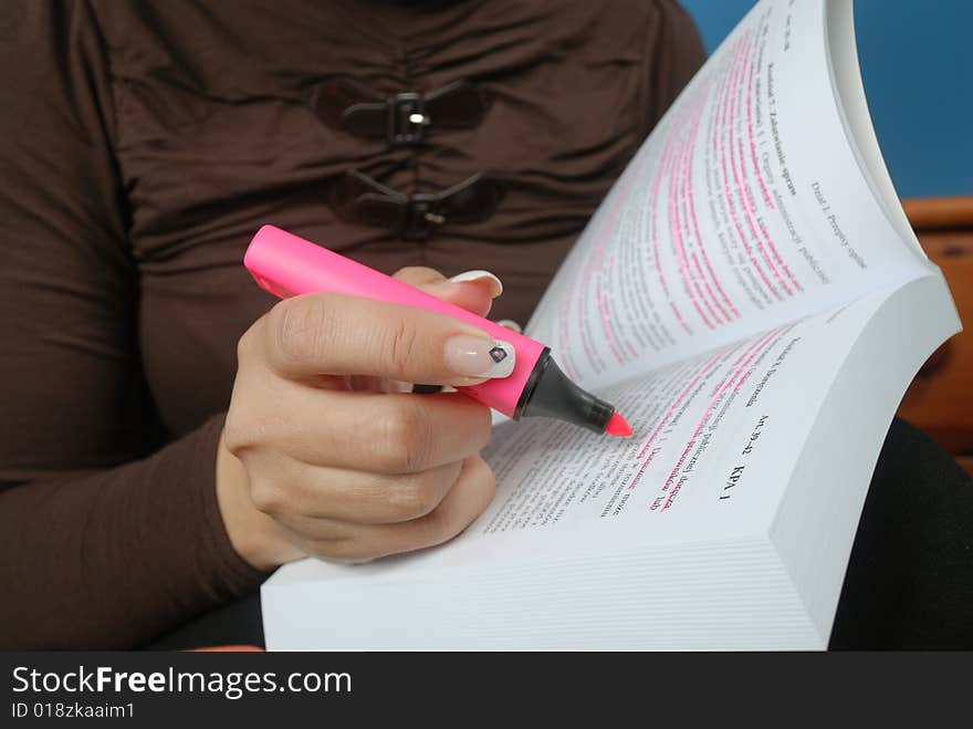 Woamn's hand with marker underlining text in book. Woamn's hand with marker underlining text in book