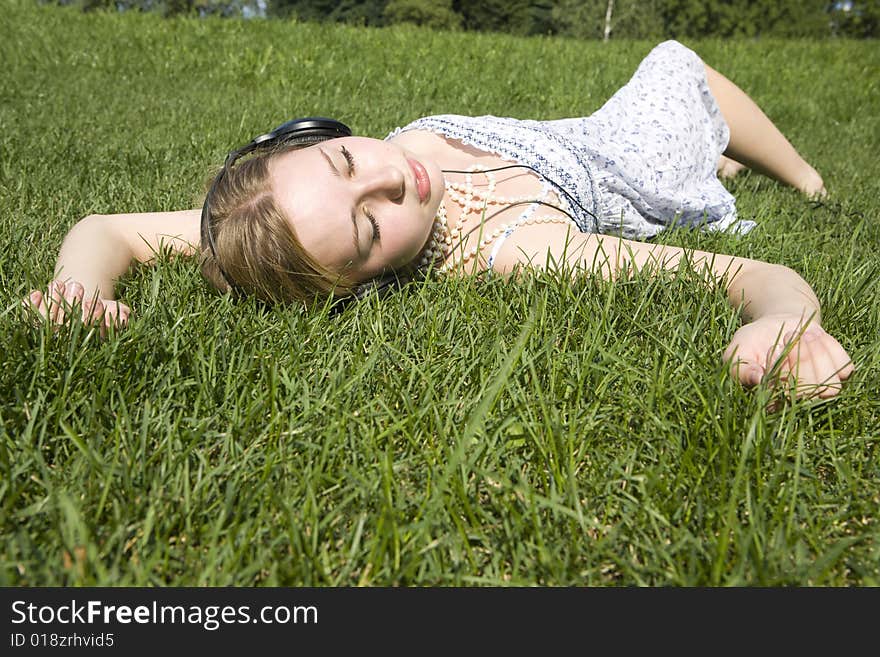 Young woman listening to music lying on grass