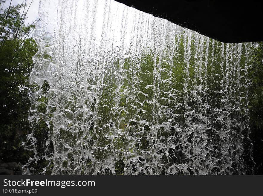 Waterfall over rocks in a forest viewed from behind the falls