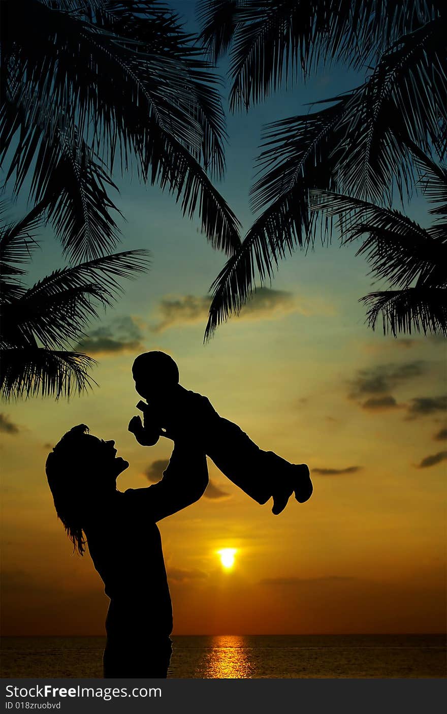 Silhouette of mother and son at sunset in tropics