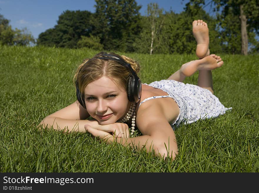 Young woman listening to music lying on grass