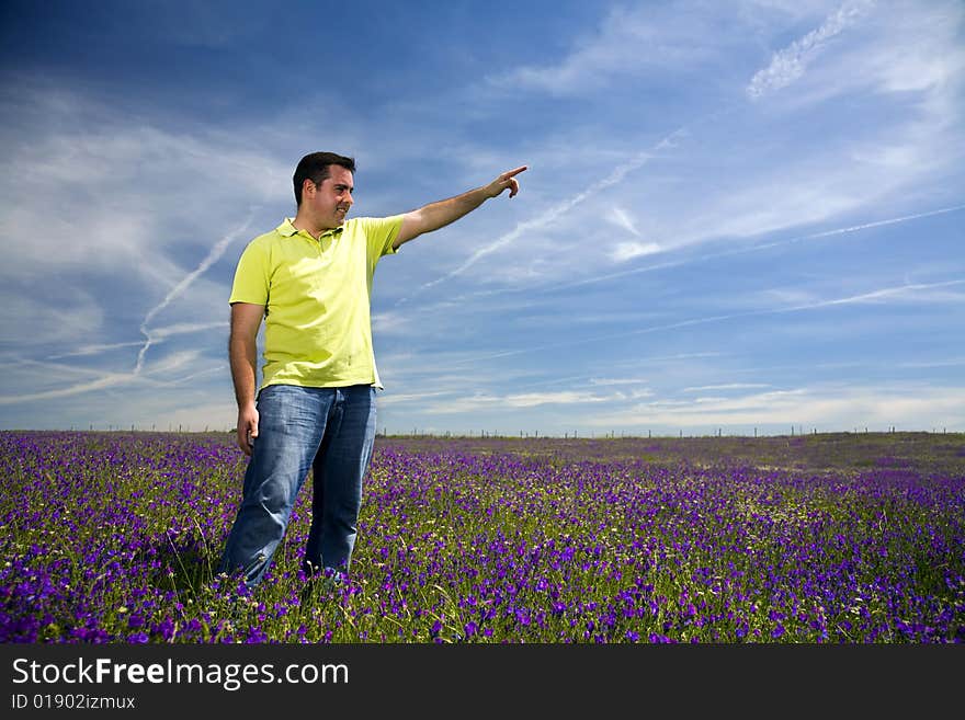 Young man in a field pointing forward with his hand