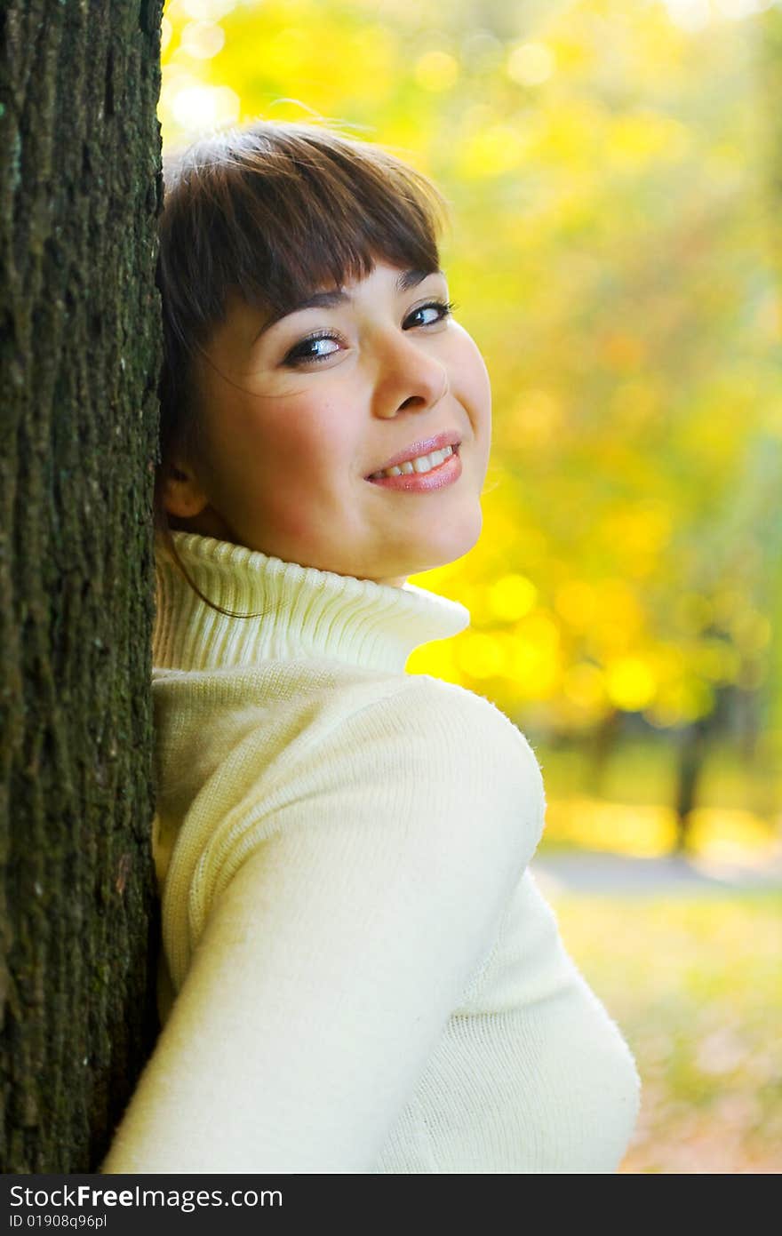 Beautiful girl smiles around tree