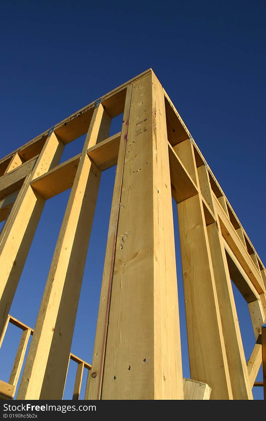 Corner of a framed house against a blue sky. Corner of a framed house against a blue sky.