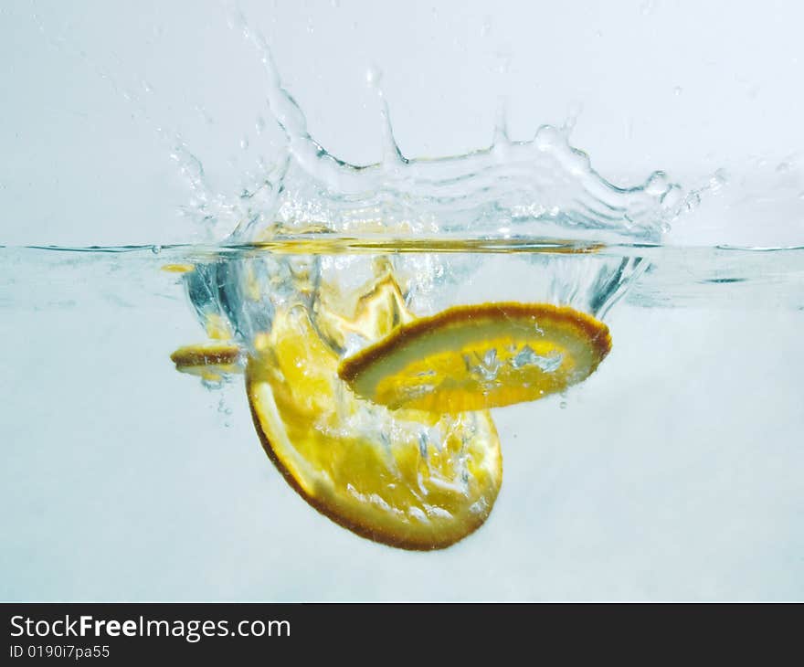 Thw slices of lemon citrus orange fruit fallin in water. Thw slices of lemon citrus orange fruit fallin in water