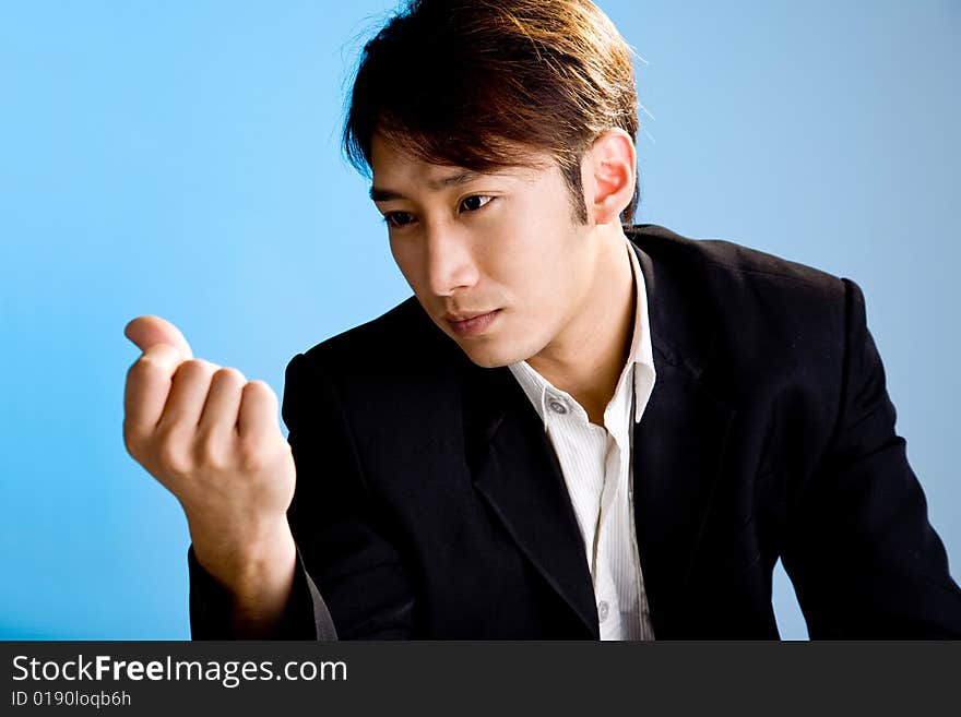 Handsome asian business man looking at his hand in formal attire. Handsome asian business man looking at his hand in formal attire