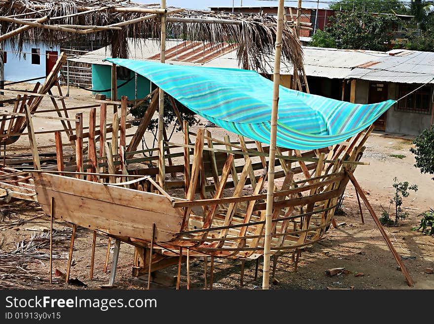 A small wooden boat is build on the shore of the Pacific Ocean. A small wooden boat is build on the shore of the Pacific Ocean